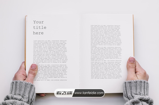 这是一款小清新风格的书本样机素材，画面中一双手捧着一本白色页面的书籍，背景是一张白色的桌子。